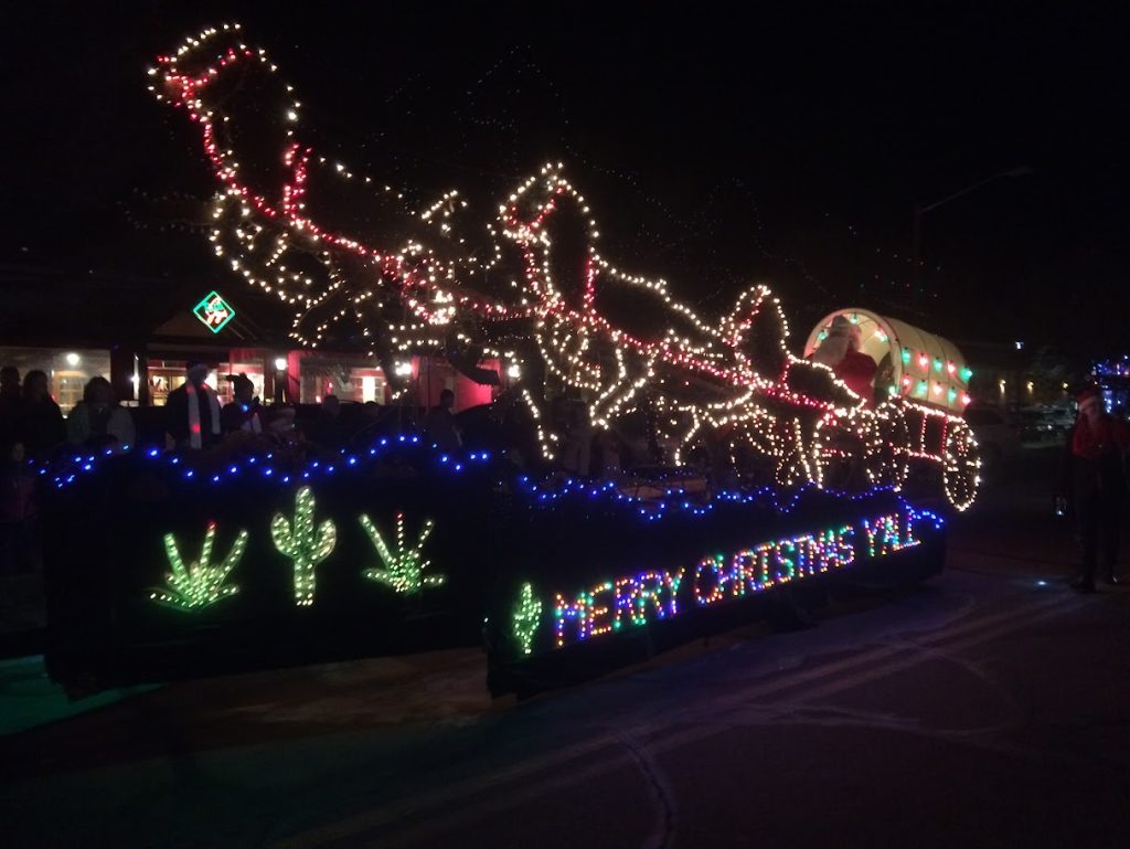 a float in the Electric Light Parade has horses and cactus and reads "Merry Christmas Y'all"