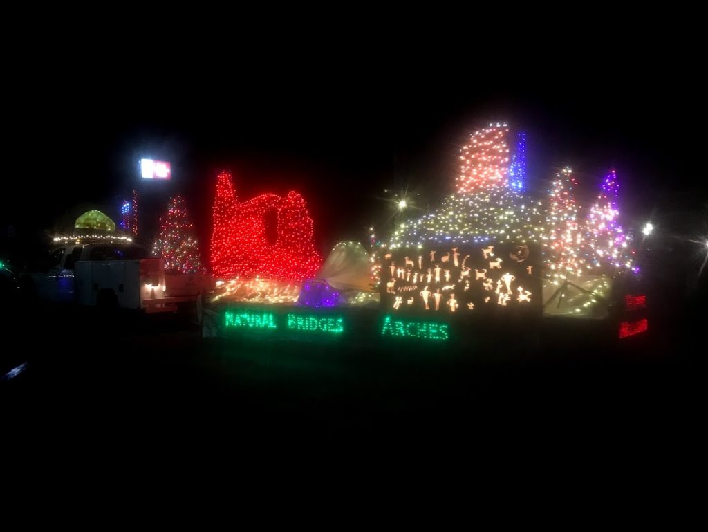 A float in the Electric Light parade shows Turret Arch and has the names of National Park units around Moab