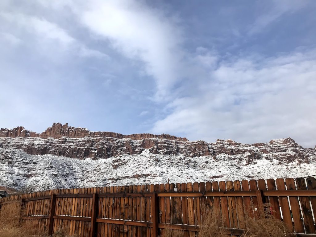 snow covers the Moab rim with some red rock underneath